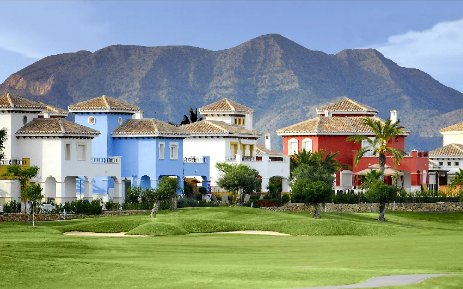 A golf course with many houses in the background.