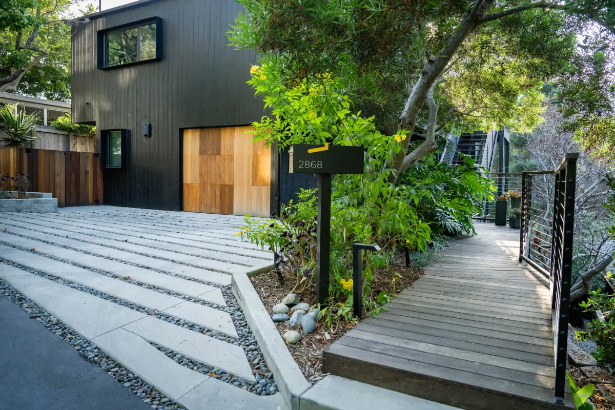 A black house with wooden steps and a tree