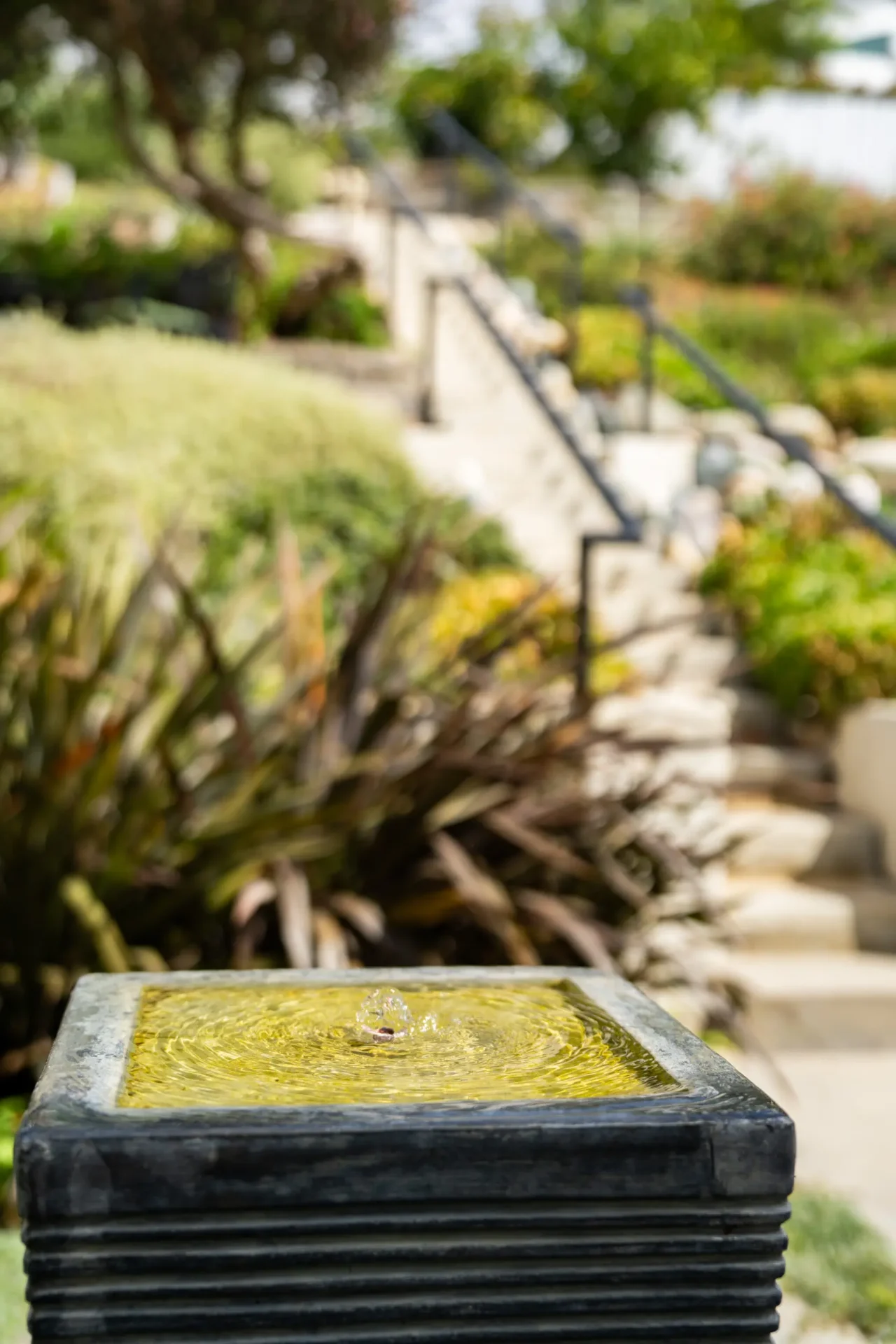 A cement planter sitting in front of some bushes.