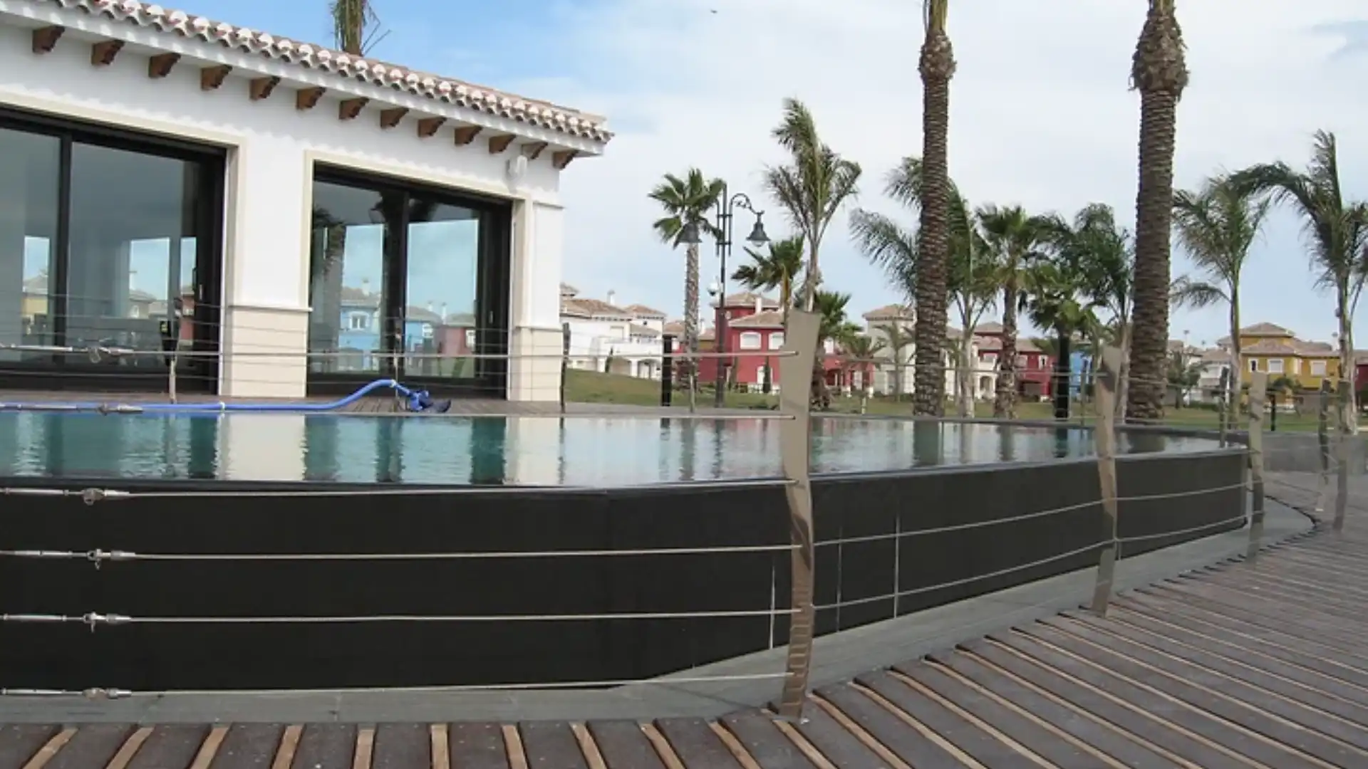 A pool with palm trees and a building in the background.