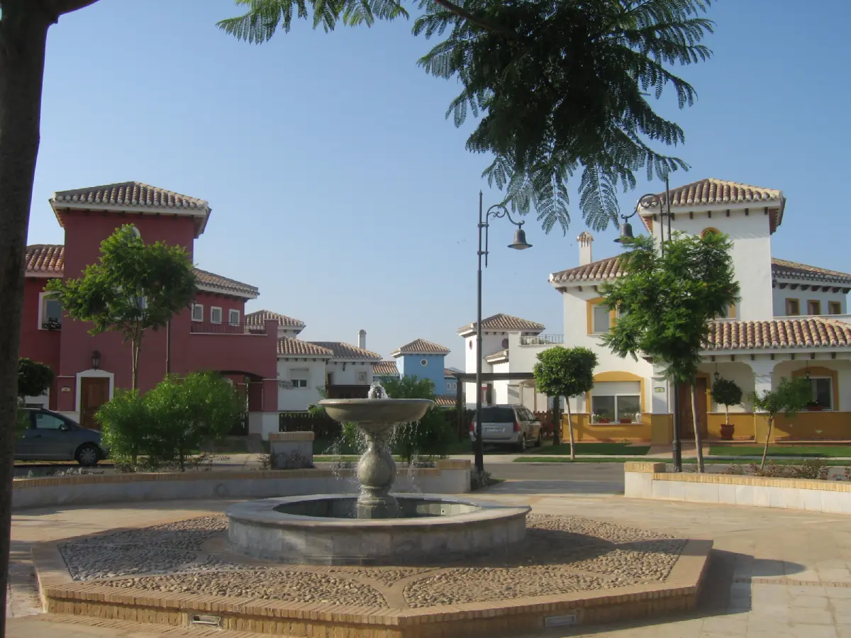A fountain in the middle of a park with many buildings.