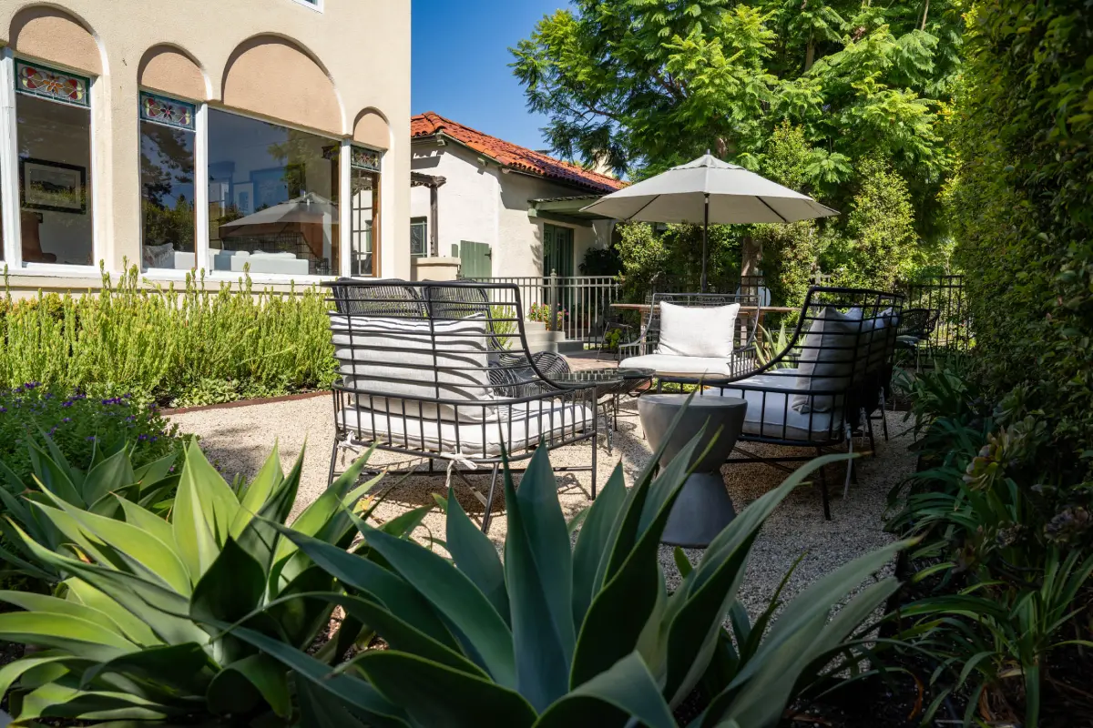 A patio with chairs and an umbrella in the background.