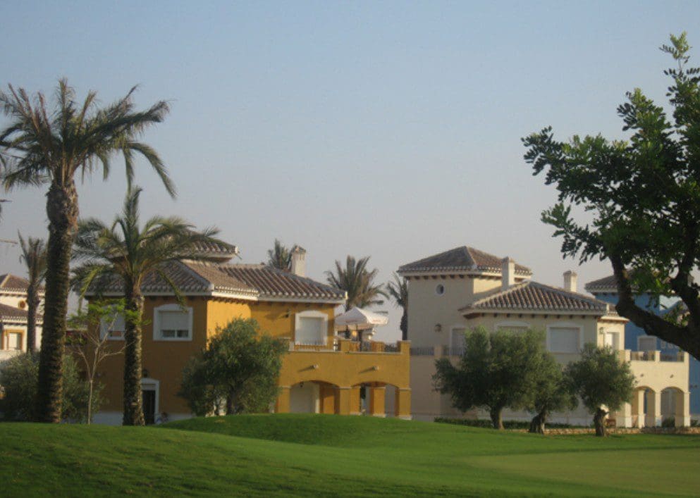 A large green field with some houses in the background