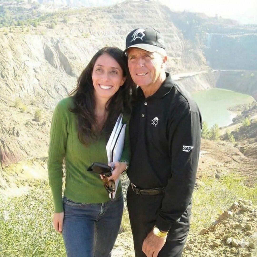 Man and woman smiling in rocky landscape.