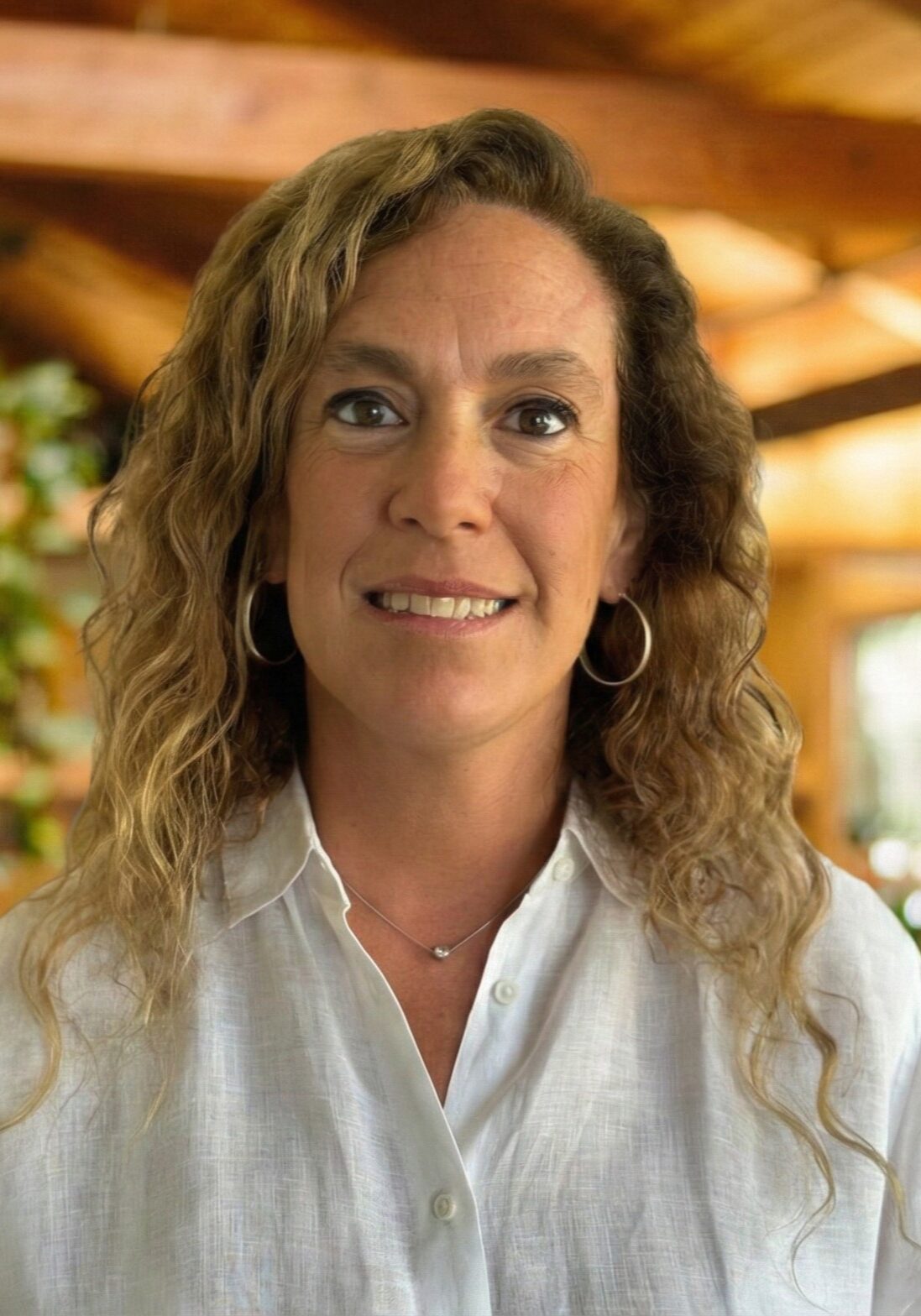 Woman smiling indoors with wooden beams background.